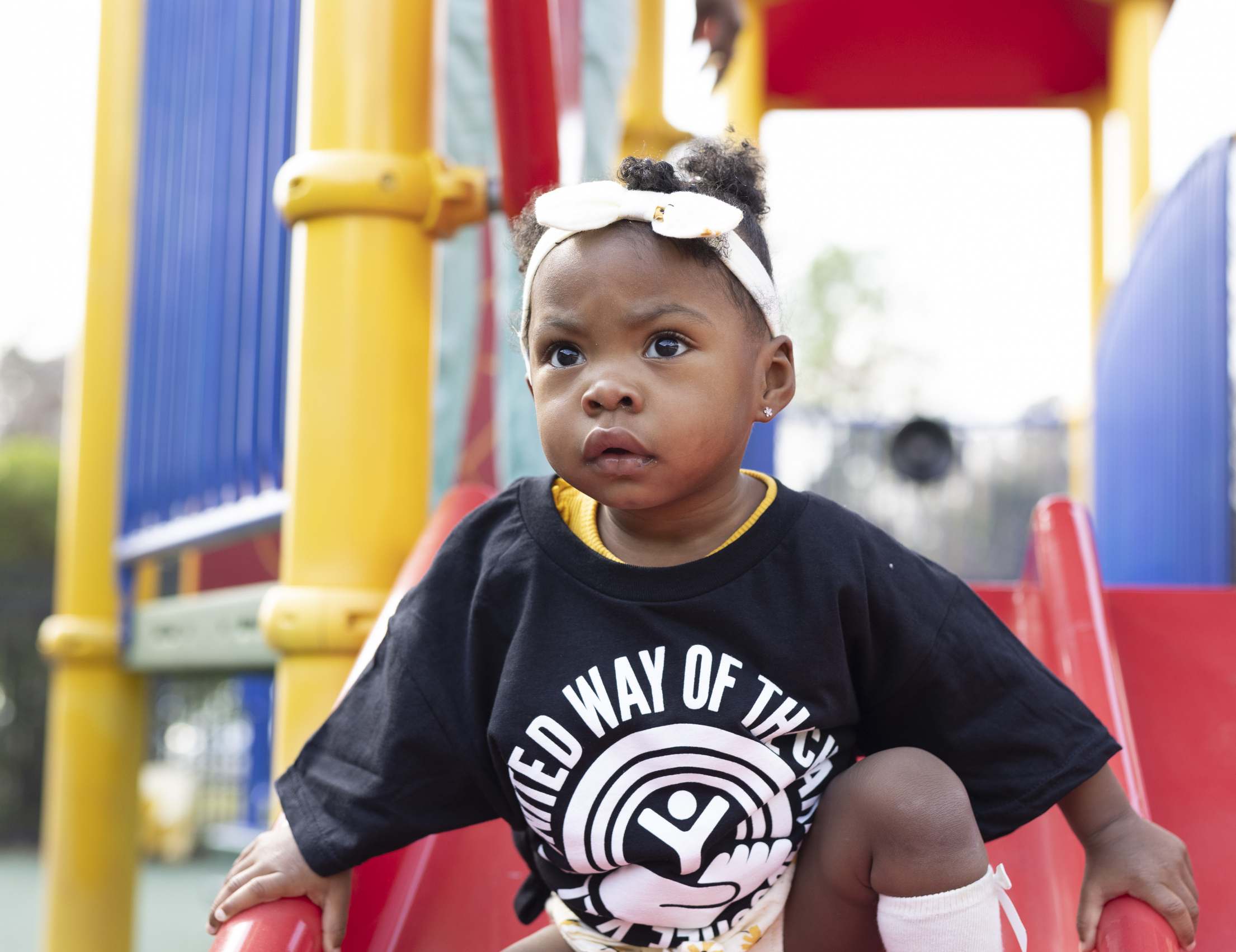 little girl wearing a black united way shirt on a slide