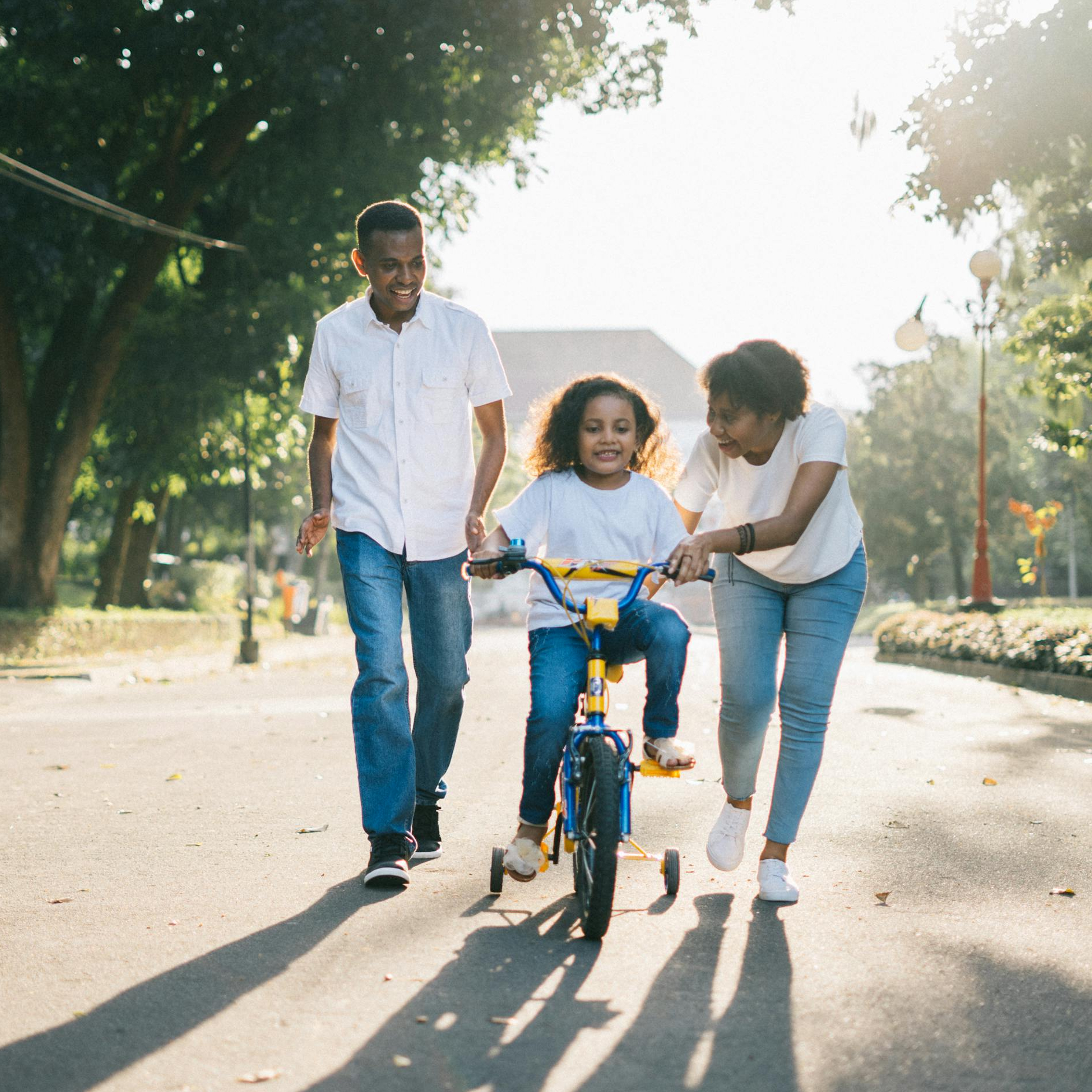 Happy family teaching their child to cycle on a sunny day outdoors.