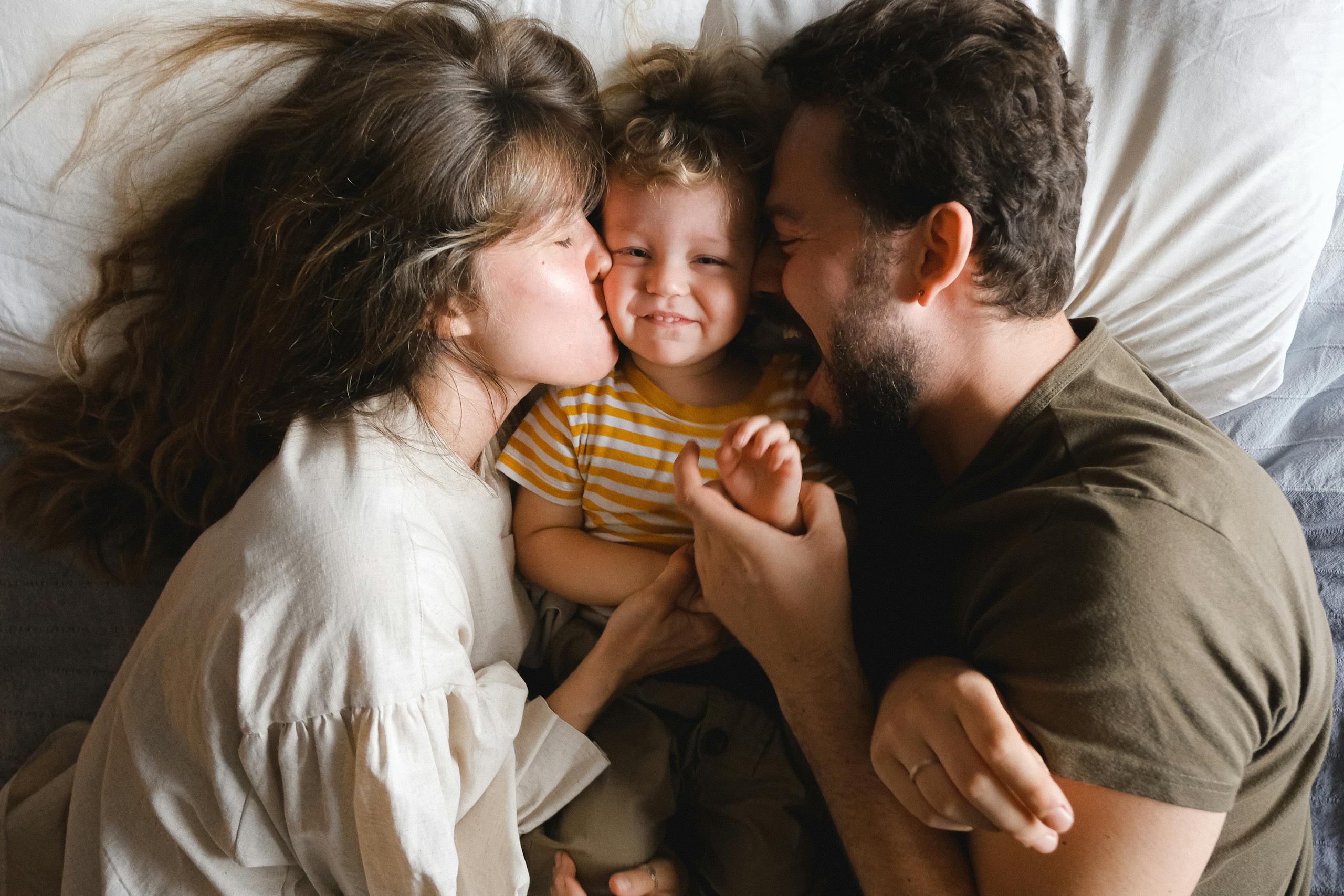 A joyful family lying together on a bed, showcasing love and happiness.