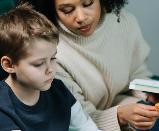A dedicated tutor helps a young boy with his homework on a laptop, fostering learning.