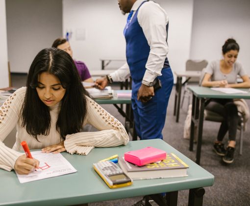 Students in a classroom during examination discussing and writing notes.